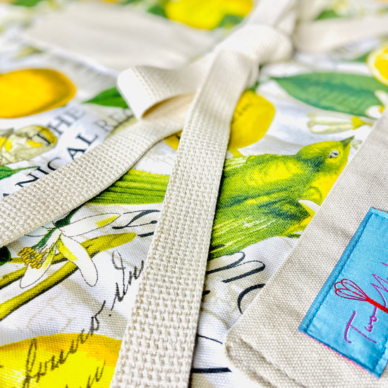 Two Medium Sized Ladies Brittany Apron yellow and green botanical print fabric lemons flowers the botanical register apron closeup view