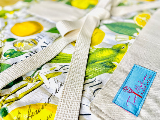 Two Medium Sized Ladies Brittany Apron yellow and green botanical print fabric lemons flowers the botanical register apron closeup view