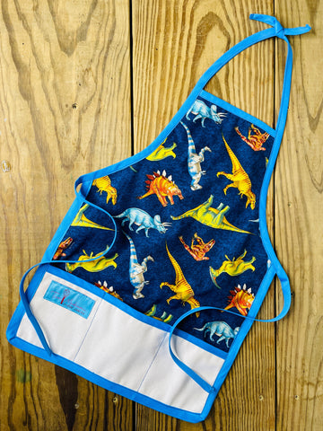 Two Medium Sized Ladies childrens dinosaurs apron stegosaurus tyrannosaurus triceratops extinct species for bake time play time blue apron strings