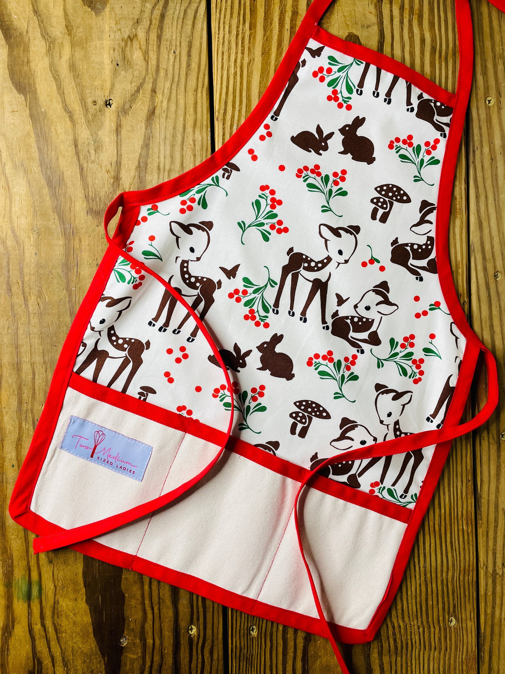 Two Medium Sized Ladies Forest Fawn Children's Christmas Apron with Reindeer Mushrooms Rabbits and Red Trim and Red Apron Strings