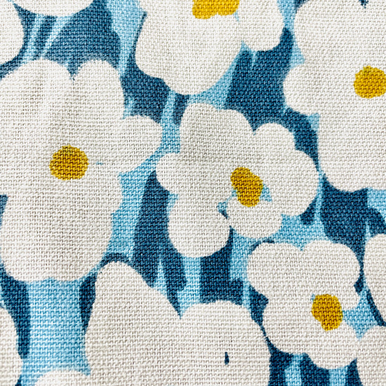 Amanda Bright Designs Bold White Floral Apron with Golden Centers on a bright blue and navy background