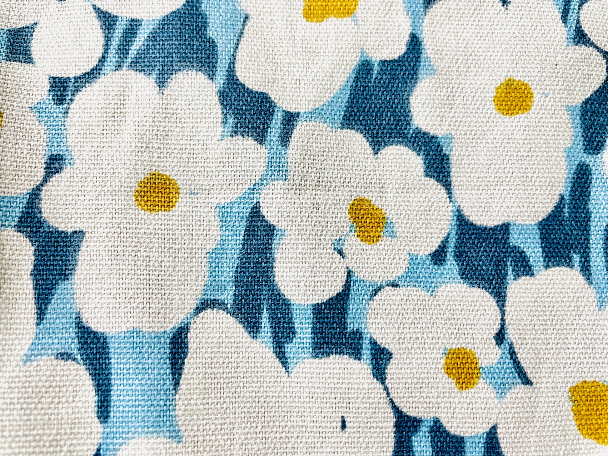 Amanda Bright Designs Bold White Floral Apron with Golden Centers on a bright blue and navy background